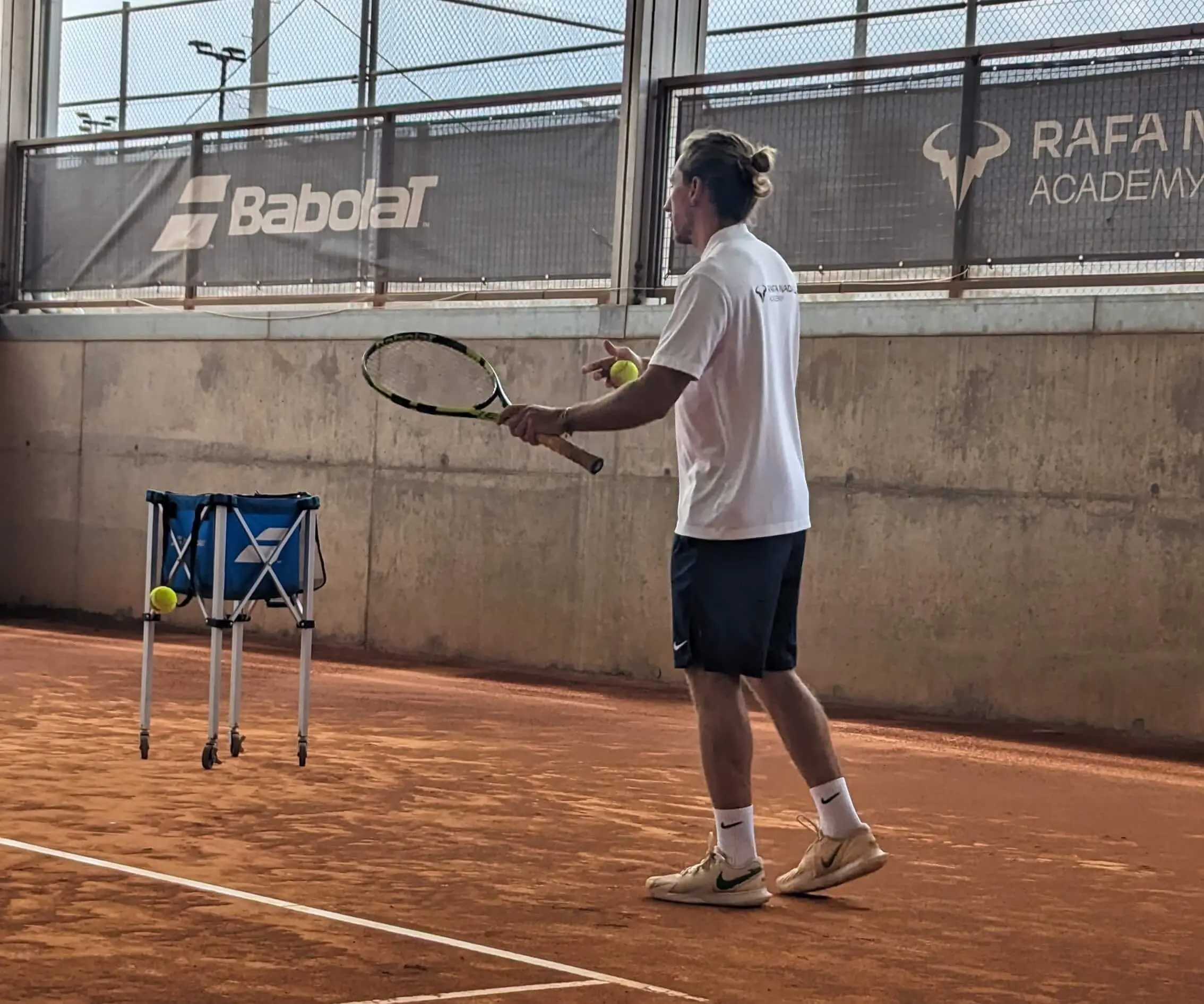 High Performance tennis coach Riccardo Leone working with a player on court, applying science based tennis training and potentially tennis cognitive training principles.